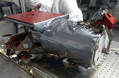 Engineers at the U.S. Naval Research Laboratory perform 
				final integration and testing on the Narrow Field Imager (NFI) in a cleanroom facility. The red hardware components are 
				protective covers that were removed before flight.